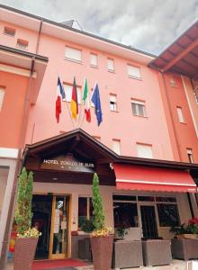 Un bâtiment rose avec des drapeaux à l'avant dans l'établissement Albergo Zoello Je Suis, à Castelvetro di Modena