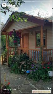 a small house with a wooden porch and flowers at Caunos bungalow in Muğla