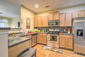a kitchen with wooden cabinets and stainless steel appliances at Macon Townhome with Patio, 5 Miles to Downtown! in Macon