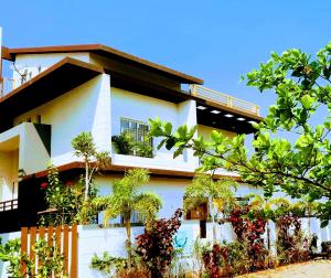 a white building with plants in front of it at KshiyOO Holiday Bungalow Resort in Pune