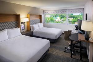 シャーロッツヴィルにあるHoliday Inn Express & Suites Charlottesville, an IHG Hotelのベッド2台、デスク、コンピュータが備わるホテルルームです。