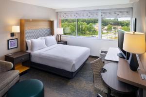 シャーロッツヴィルにあるHoliday Inn Express & Suites Charlottesville, an IHG Hotelのベッド、デスク、コンピュータが備わるホテルルームです。