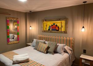1 dormitorio con 1 cama y una pintura en la pared en Hotel Colonial Tafi del Valle by DOT Tradition en Tafí del Valle