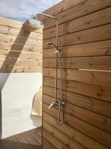 a shower in a bathroom with a wooden wall at Casa dos Retratos Faro in Faro