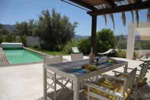 un tavolo e sedie su un patio con piscina di Melegis 1-Bed Cottage Sleeps 2 Pool & Garden a Melegis