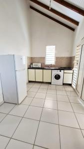 eine Küche mit weißen Geräten und weißem Fliesenboden in der Unterkunft KAZ's à l'Anse Maurice in Gros Cap