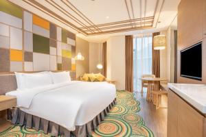 Holiday Inn Resort Yichun Mingyue Mountain, an IHG Hotel في Yichun: غرفة فندق بسرير ابيض كبير ومطبخ