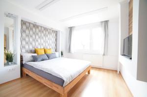 a white bedroom with a bed and a television at comfort 66 in Miskolc