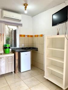 a kitchen with a refrigerator and a tv on the wall at Sol Mar in Praia do Rosa