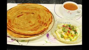 a plate with two pancakes and a cup of tea at Hotel Taj Palace Multan in Multan