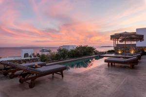 una piscina con bancos y vistas al océano en Trinity Mykonos - Villa & Beachfront Boutique Hotel en Platis Gialos