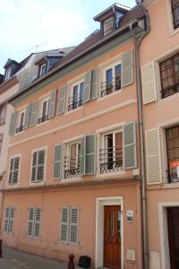 a pink building with white windows and shutters at Les Fleurs de Thann in Thann