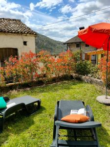 eine Terrasse mit einem roten Regenschirm, 2 Stühlen und einem Tisch in der Unterkunft Da Massimo-Casa Šimulni in San Leonardo