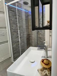 ein weißes Badezimmer mit einem Waschbecken und einem Spiegel in der Unterkunft Da Massimo-Casa Šimulni in San Leonardo