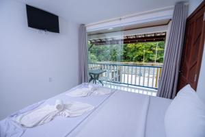 a bedroom with a bed and a balcony with a television at Hotel do Pescador in Morro de São Paulo