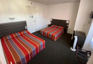 a hotel room with two beds and a door at Hôtel Métropole in Lourdes