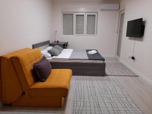 um quarto com uma cama, um sofá e uma televisão em Apartment Diamond em Podgorica