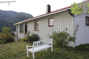 a white bench sitting in front of a house at Landlig hus på kysten in Tustna