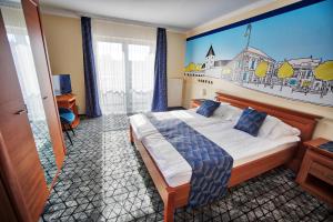 1 dormitorio con 1 cama con una pintura en la pared en Hotel Viktória en Sárvár