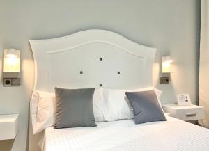 białe łóżko z białym zagłówkiem i 2 poduszkami w obiekcie Hostal Los Ángeles w Madrycie