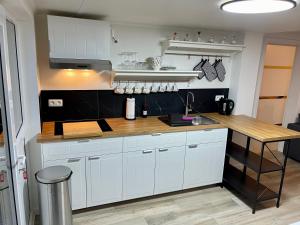 a kitchen with white cabinets and a wooden counter top at Le berceau de charmes in La Reid