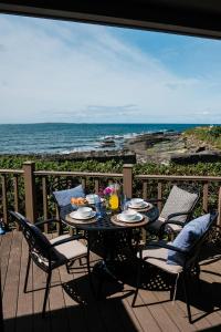 a table on a deck with a view of the ocean at Armada Cottages in Spanish Point