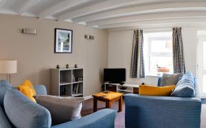 a living room with two blue couches and a tv at Bwthyn Gweilch in Machynlleth