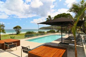 a patio area with a pool and chairs at Seahaven Noosa Beachfront Resort in Noosa Heads