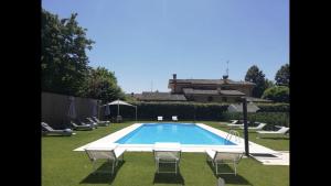 a swimming pool with chairs and a house in the background at Villa Petra in Novellara