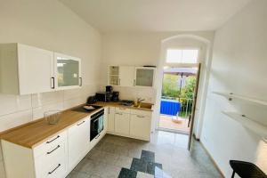 a kitchen with white cabinets and an open door at FeWo Seestadt mit Balkon in Goslar