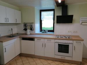 a kitchen with white cabinets and a sink and a window at Knoofs in Schwirzheim