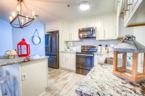 a kitchen with white cabinets and a red chandelier at BRAND NEW! Laketown Wharf 633! Amazing 3 BD, Great Location, And Awesome Amenities! in Panama City Beach