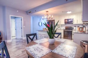 a kitchen and dining room with a wooden table with a plant at BRAND NEW! Laketown Wharf 633! Amazing 3 BD, Great Location, And Awesome Amenities! in Panama City Beach