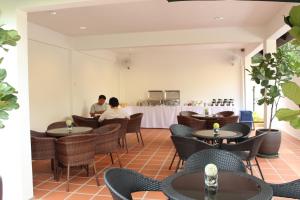 a restaurant with tables and chairs and a person in the background at Song Service Apartment formerly known as Jinhold Service Apartment in Kuching