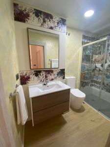 a bathroom with a sink and a toilet and a mirror at Apartamentos de Don Juan in Úbeda +34 photos