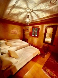 - une chambre avec 3 lits et un lustre dans l'établissement Riad Tourtit, à Imlil