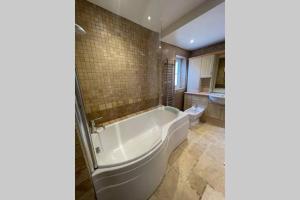 La salle de bains est pourvue d'une grande baignoire et de toilettes. dans l'établissement Charming, cosy waterside retreat in Gimingham, North Norfolk, à Gimingham