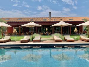 a pool with chairs and umbrellas next to a house at Santa Lucia Maccarese - Residenza Agricola in Maccarese