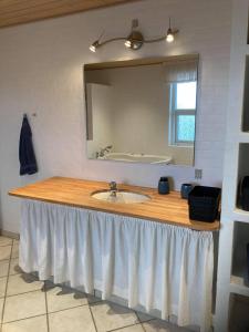 um balcão de casa de banho com um lavatório e um espelho em Bakkebo em Hvide Sande