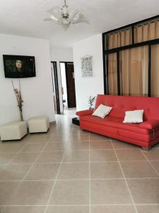 - un canapé rouge dans le salon doté de carrelage dans l'établissement hotel villa morenta, à Yopal