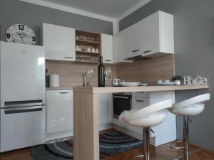 a kitchen with white cabinets and white stools at Apartment Sve u 5 minuta in Zadar