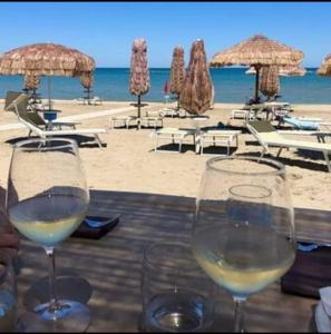 two glasses of wine sitting on a table near the beach at Greta a mare in Montesilvano