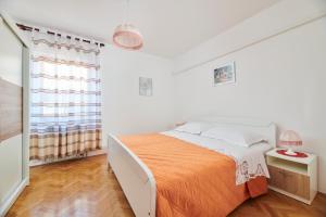 um quarto branco com uma cama com um cobertor laranja em Haus Ana em Porec