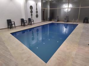 - une grande piscine d'eau bleue dans une pièce avec des chaises dans l'établissement Opéra Appartement, Hivernage Marrakech., à Marrakech