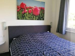 ノールトウェイクにあるBright Holiday Home in Noordwijk near Seaの赤い花の絵画が飾られたベッドルーム1室