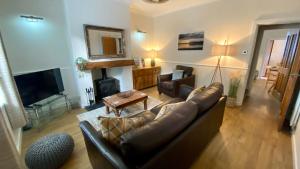 a living room with a leather couch and a television at Riverside Cottage in Whalley