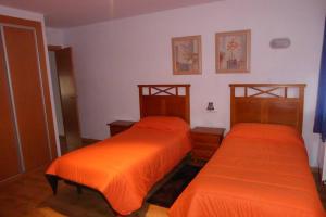2 letti in una camera con lenzuola arancioni di Casa Rural El Silvestrito a Valdejeña