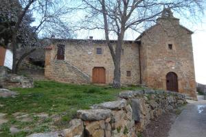 un antico edificio in pietra con un muro di pietra e un edificio con due porte di Casa Rural El Silvestrito a Valdejeña