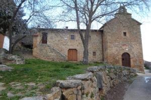 stary kamienny budynek z kamienną ścianą i budynek z dwoma drzwiami w obiekcie Casa Rural El Silvestrito w mieście Valdejeña