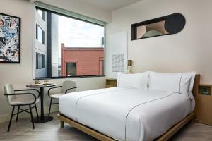 a bedroom with a bed and a table and a window at Catbird Hotel in Denver